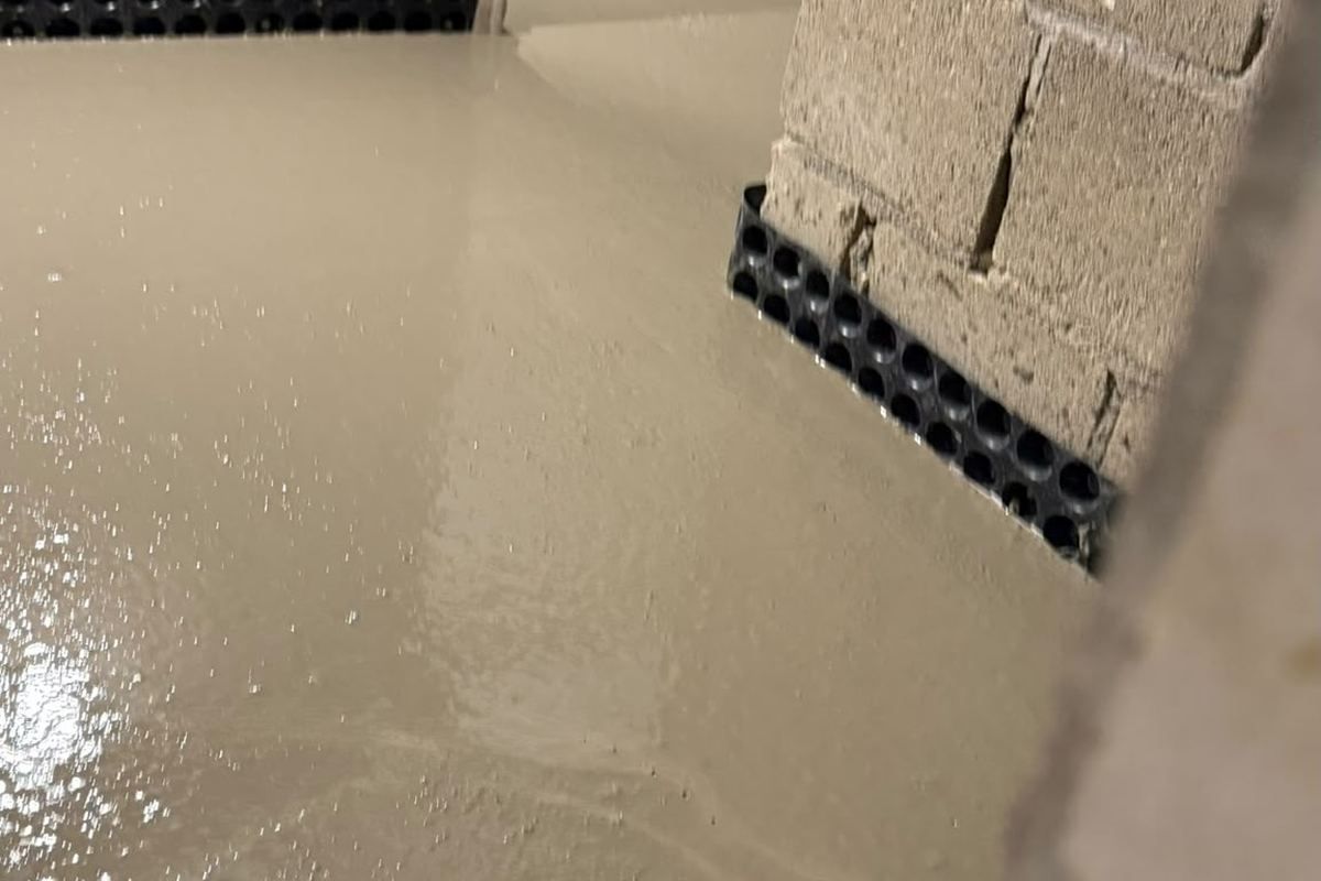 Keldervloer met verse cementlaag over de drainage en het noppenmembraan langs de muren, door Aqua-Block