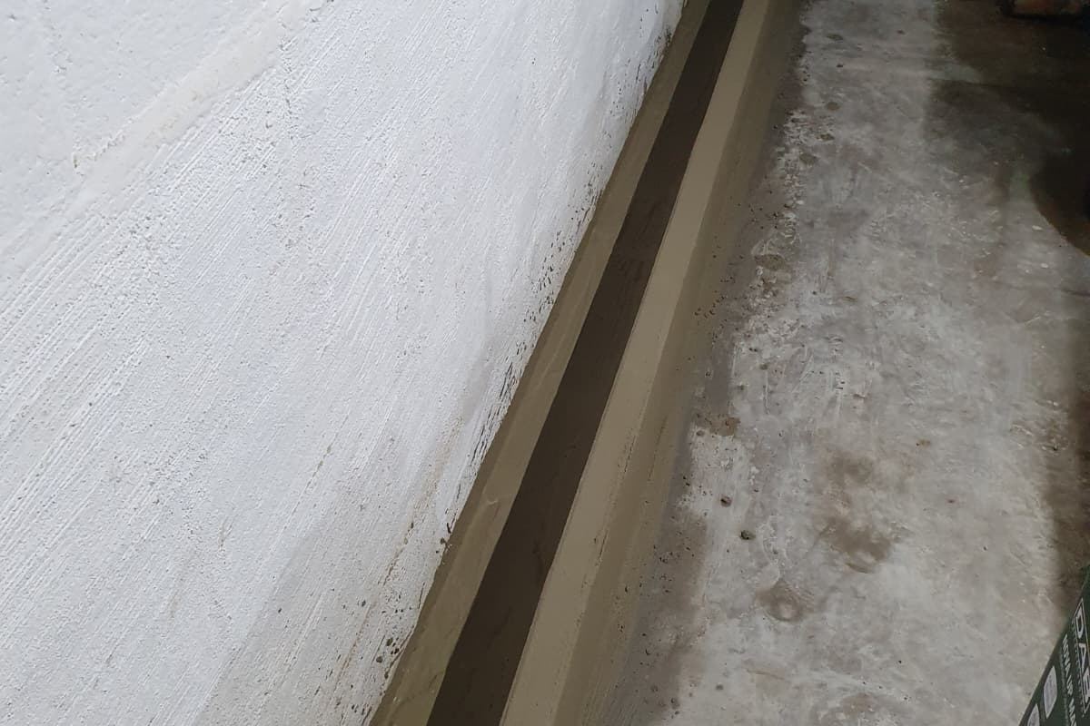 Gemetste goot met waterdicht cement langs de keldermuur voor randdrainage door Aqua-Block