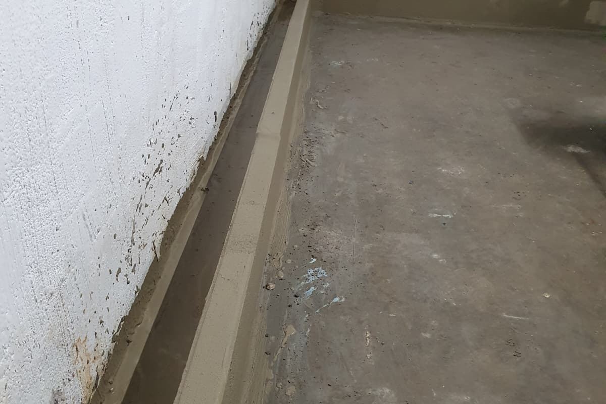 Gemetste goot langs de naad tussen keldermuur en vloer, werk van Aqua-Block