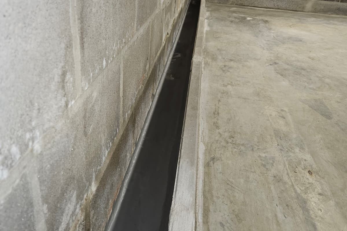 Gemetste goot voor randdrainage in een kelder, werk van Aqua-Block